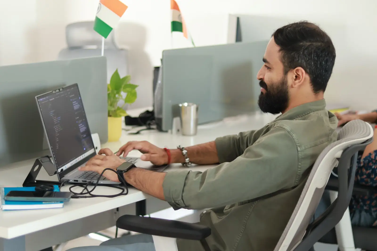A developer writing code on a laptop in a bright office